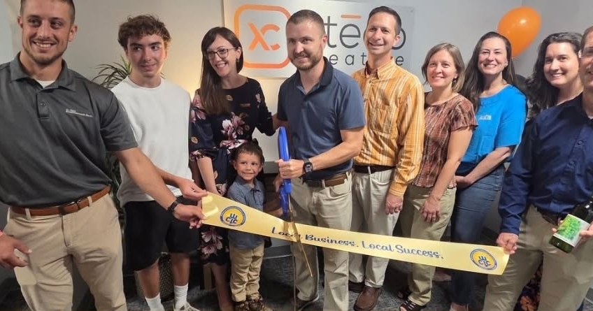 Guests holding the gold "Local Business. Local Success." ribbon in front of the Xtego Creative sign at 330 Pine Street