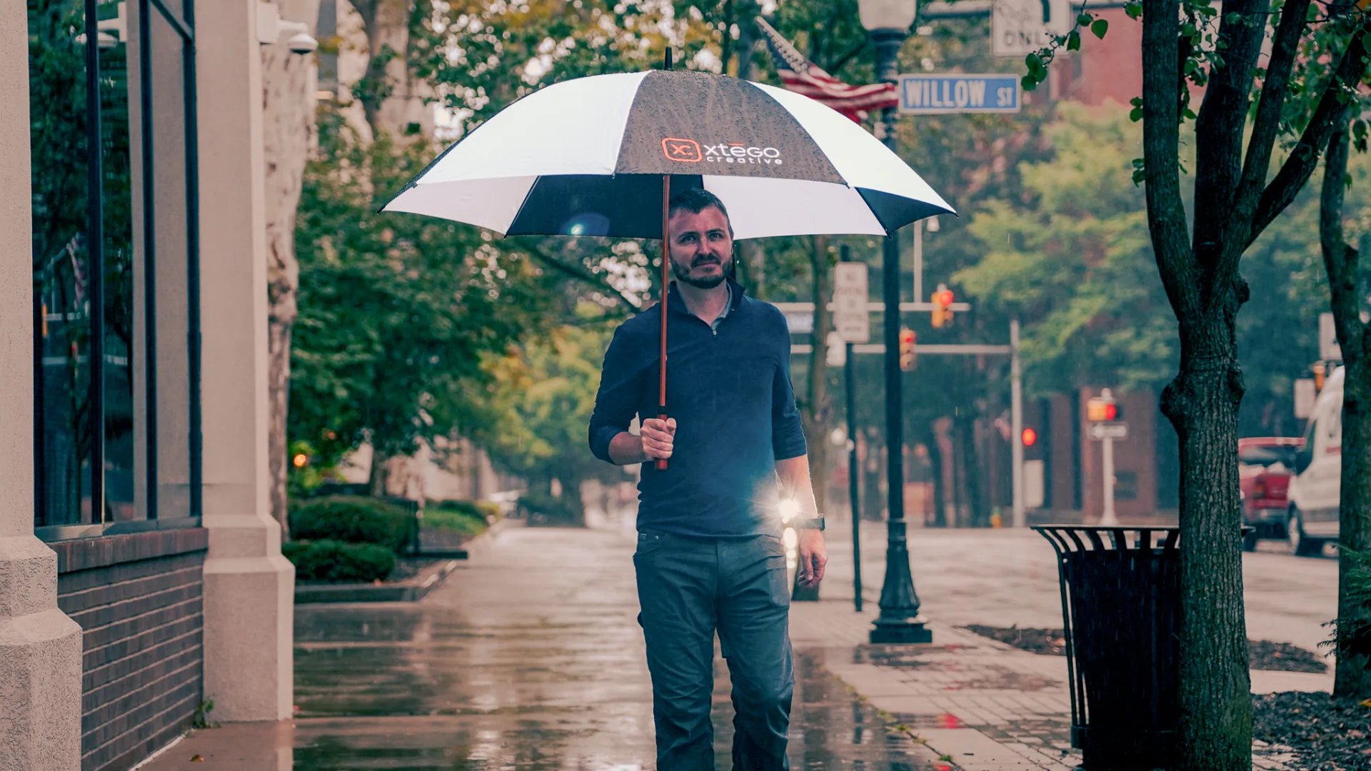 Curtis Steinbacher holding an Xtego Creative umbrella on a rainy sidewalk in downtown Williamsport, PA